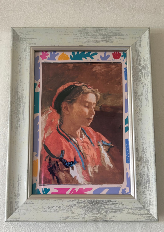 Framed portrait of a person with a colorful abstract border on a plain wall.